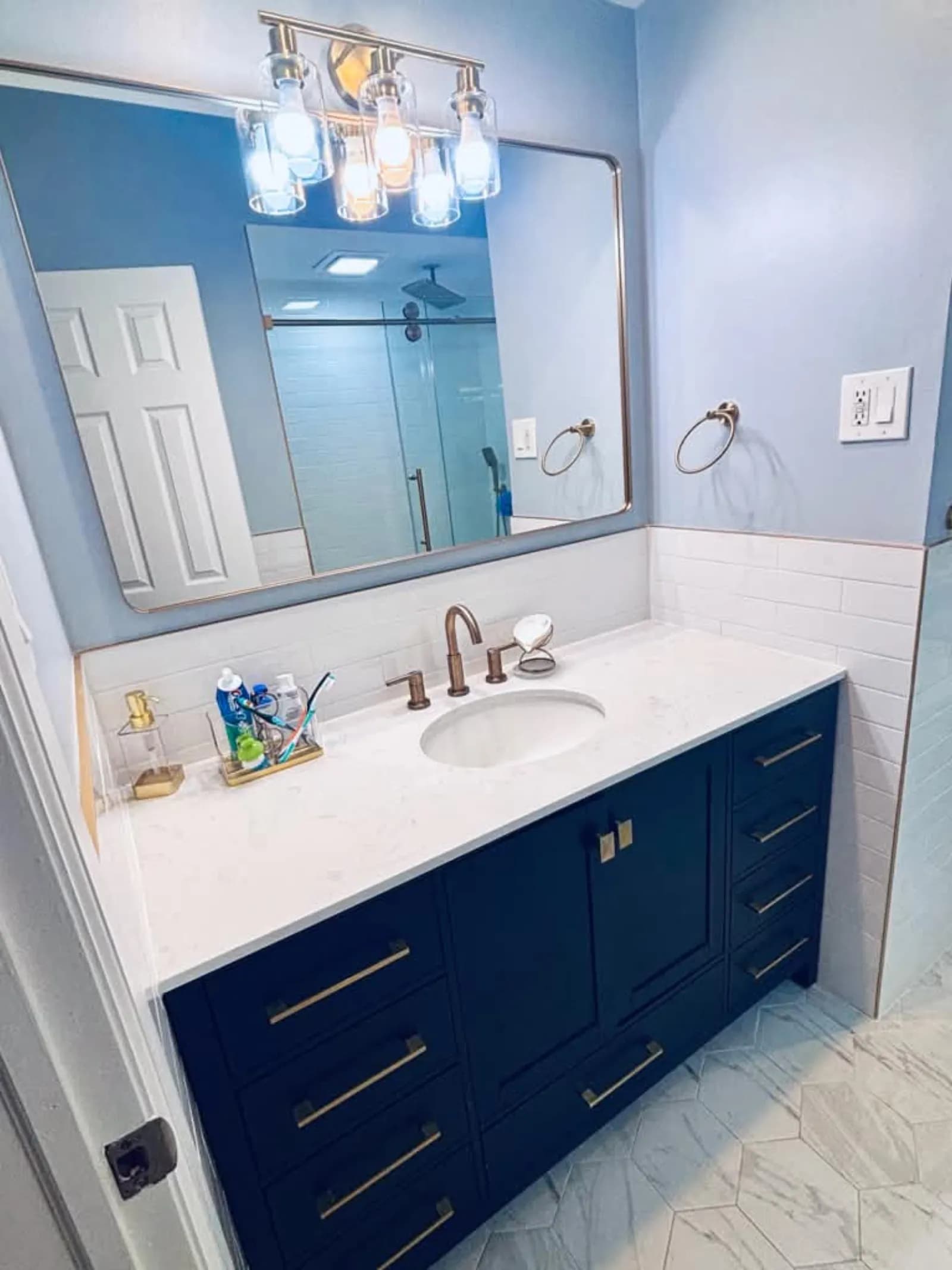 Bathroom with navy vanity, brass hardware, subway tile and a large hexagon floor tile