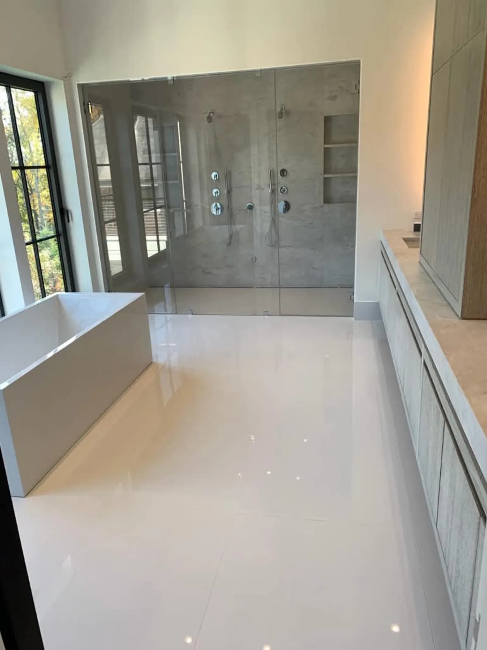 Primary bathroom with freestanding tub, polished porcelain floor and a double glass shower