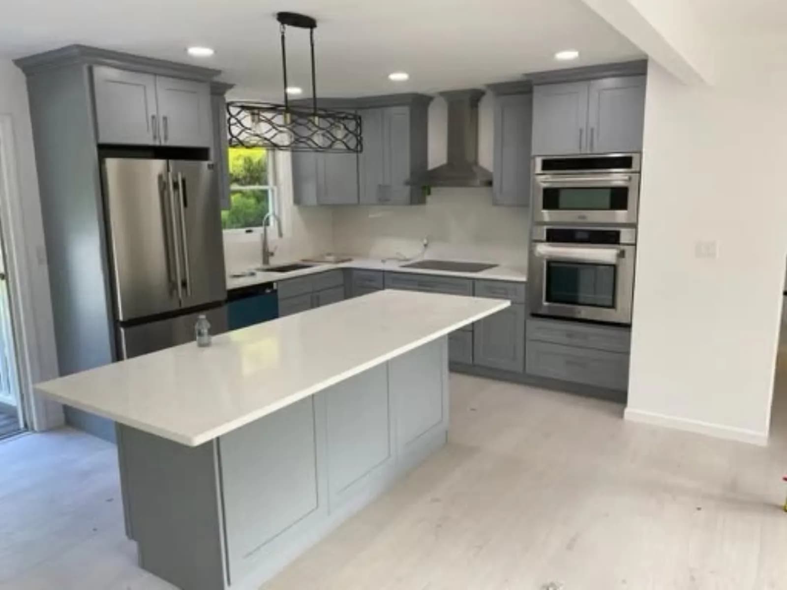 Kitchen with gray cabinets, white quartz island, stainless appliances and wall oven