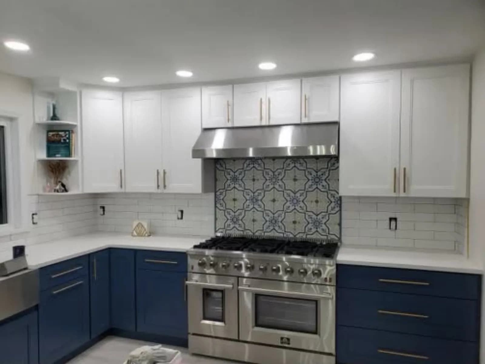 Kitchen with navy base cabinets, white uppers and a patterned tile range backsplash