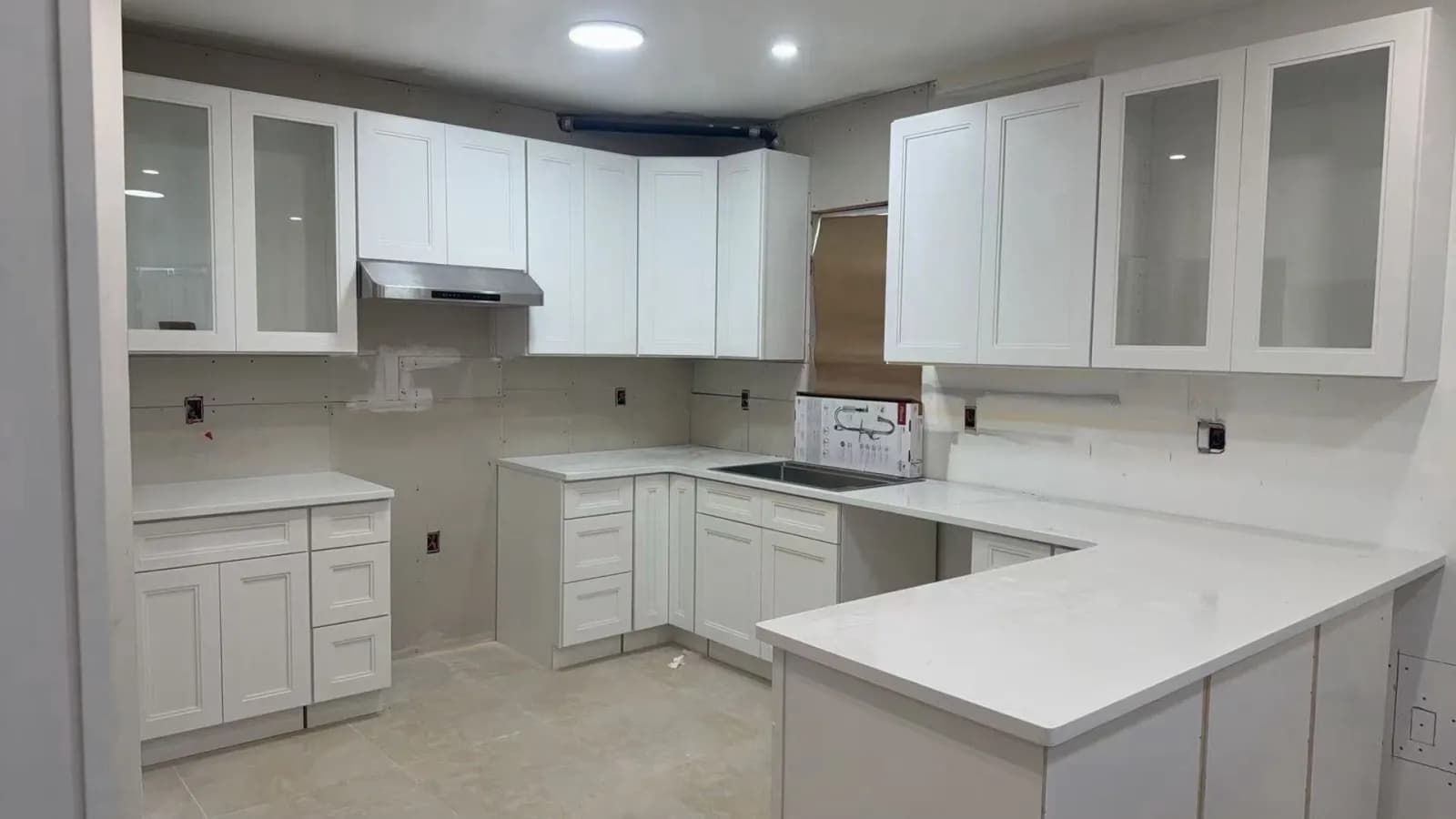 Kitchen with white shaker cabinets and a U-shaped quartz countertop during installation