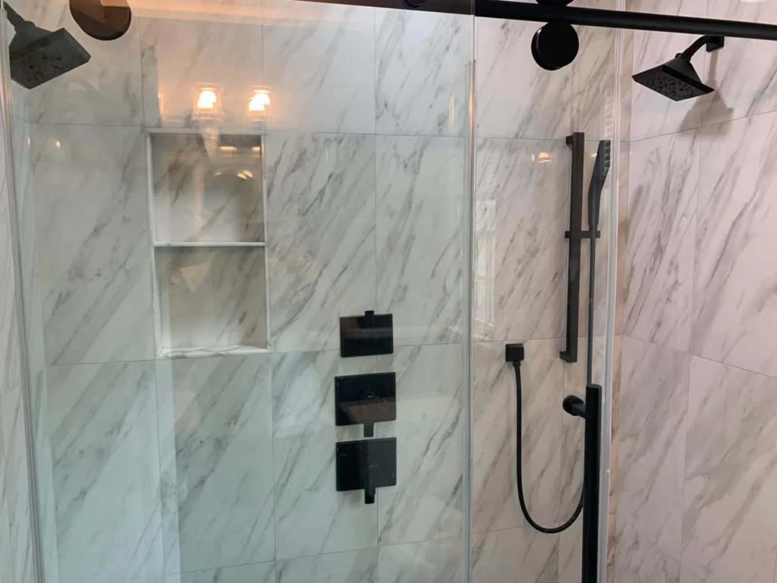 Shower with marble-look tile, recessed niche and matte black fixtures